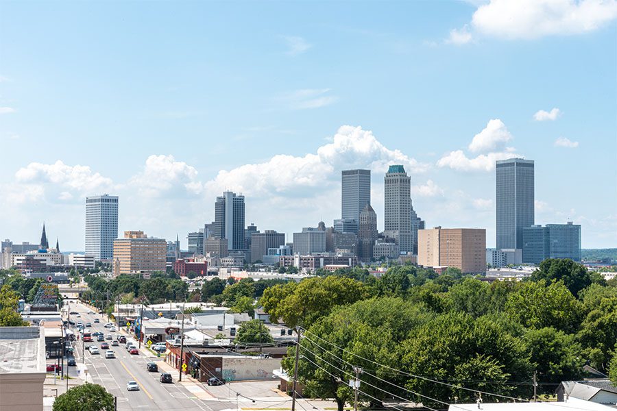 Tulsa, OK - View of Downtown Tulsa Oklahoma on a Sunny Day with Views of Green Trees Surrounding Commercial Buildings and Views of Skyscrapers in the Background